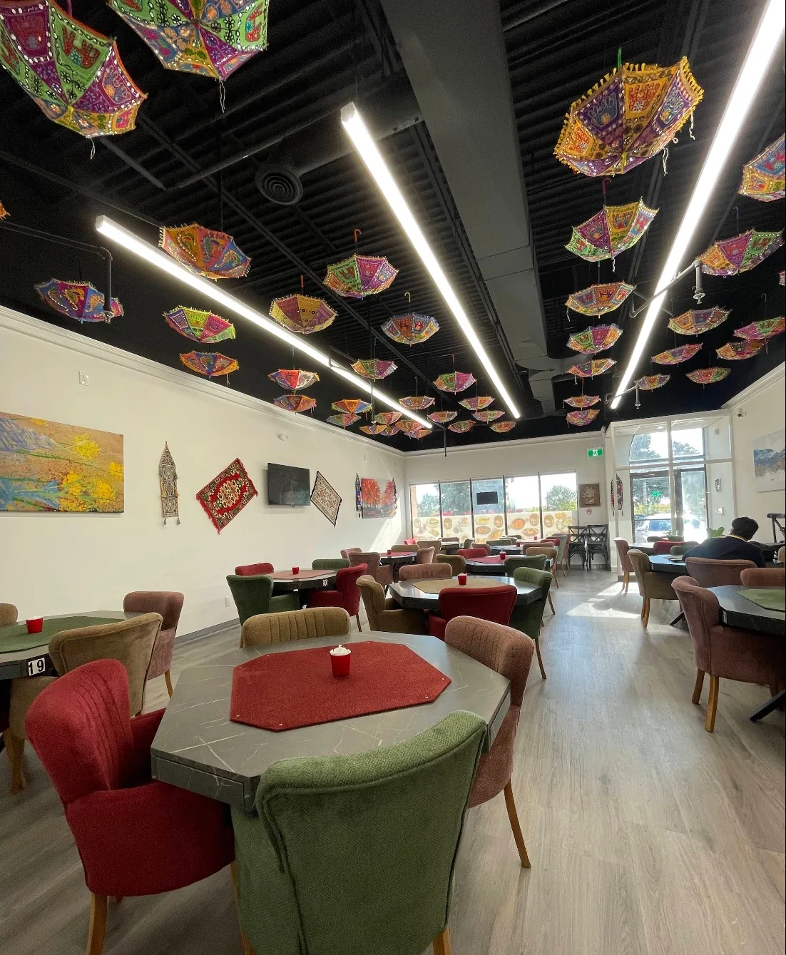 The finished Café Luka dining room looking toward the storefront windows, furnished with tables and upholstered chairs