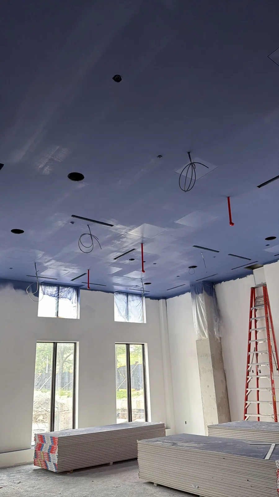 High open commercial ceiling sprayed in a deep navy finish above tall windows — FAIME ceiling repaint in Scarborough