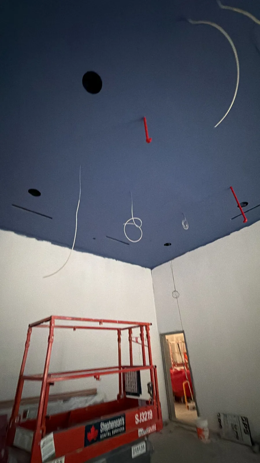Mid-job view of the navy ceiling with the lift in frame during the spray work