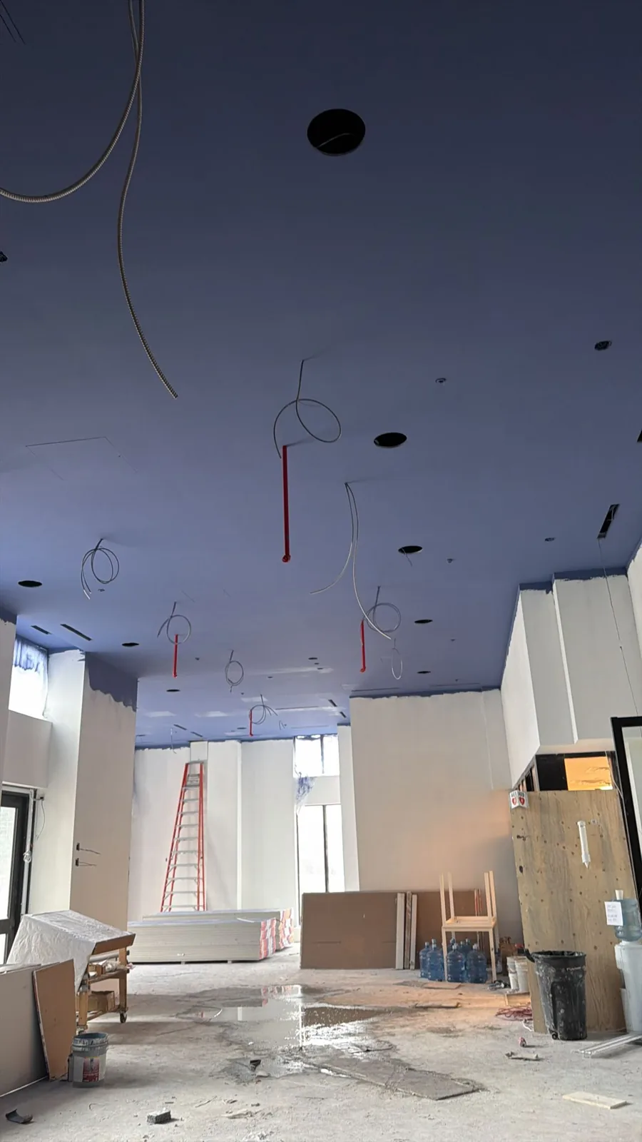 Upward view of the tall sprayed navy ceiling with conduit and sprinkler drops