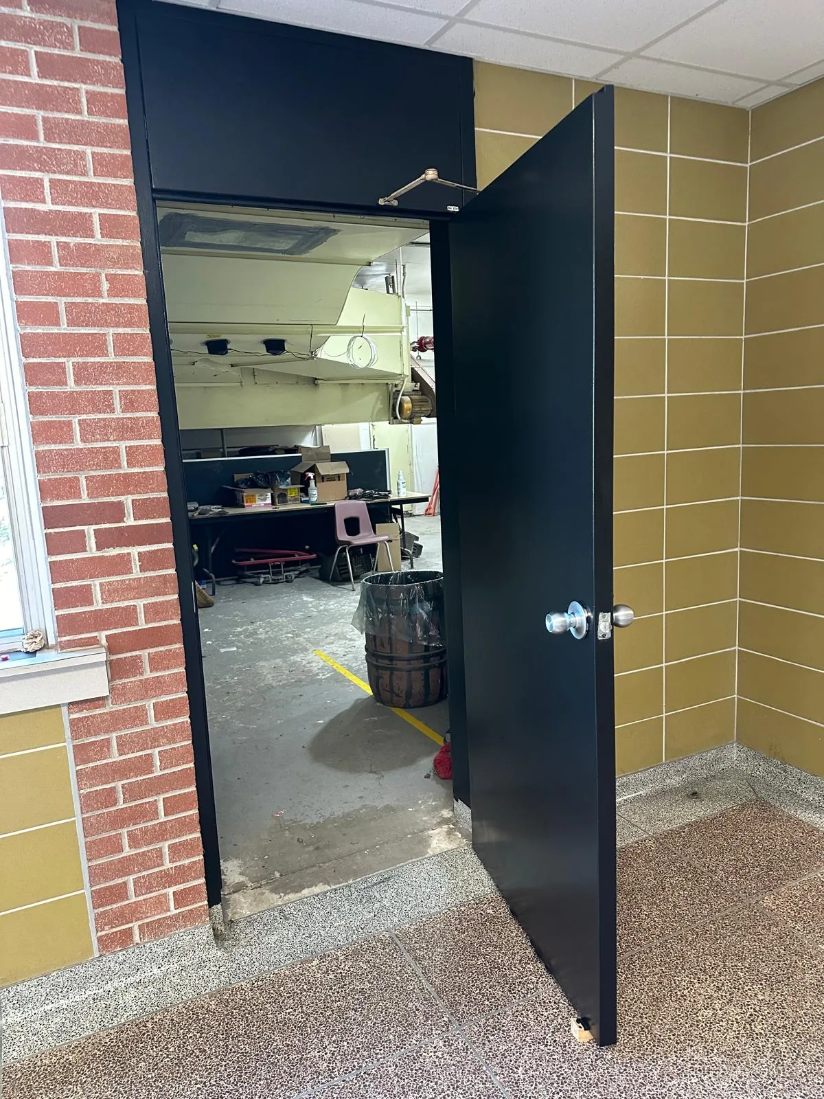 A black-finished door and frame opening into a school workshop