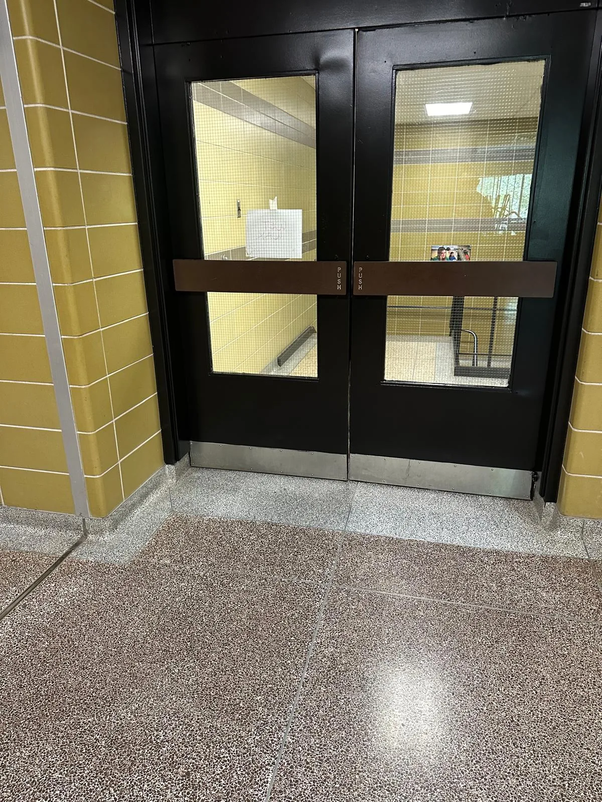 A pair of glazed corridor doors and frame finished in black between tiled walls