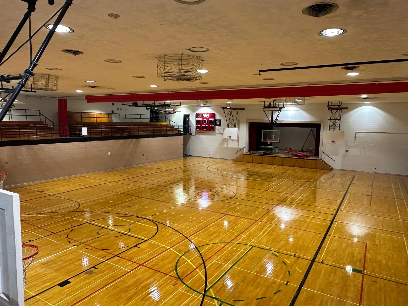 The gymnasium from the opposite corner, showing the repainted walls, bleachers and stage end