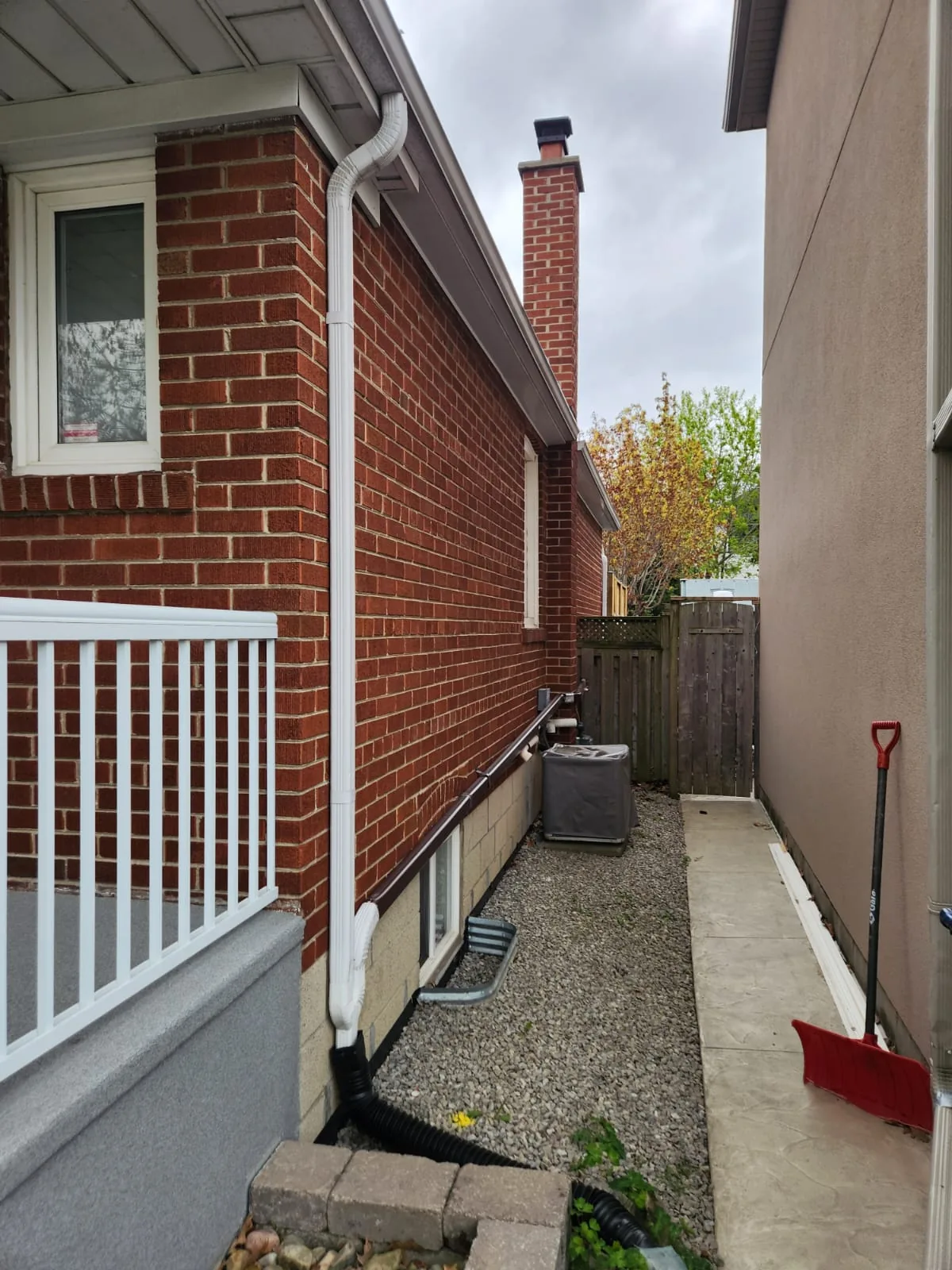 Before: the side of the house in red brick with white downspouts and trim
