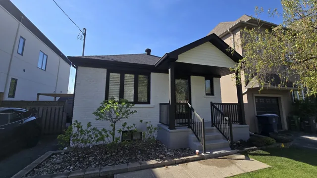 An Etobicoke bungalow after a full exterior repaint, with white painted brick and black windows, railings and trim