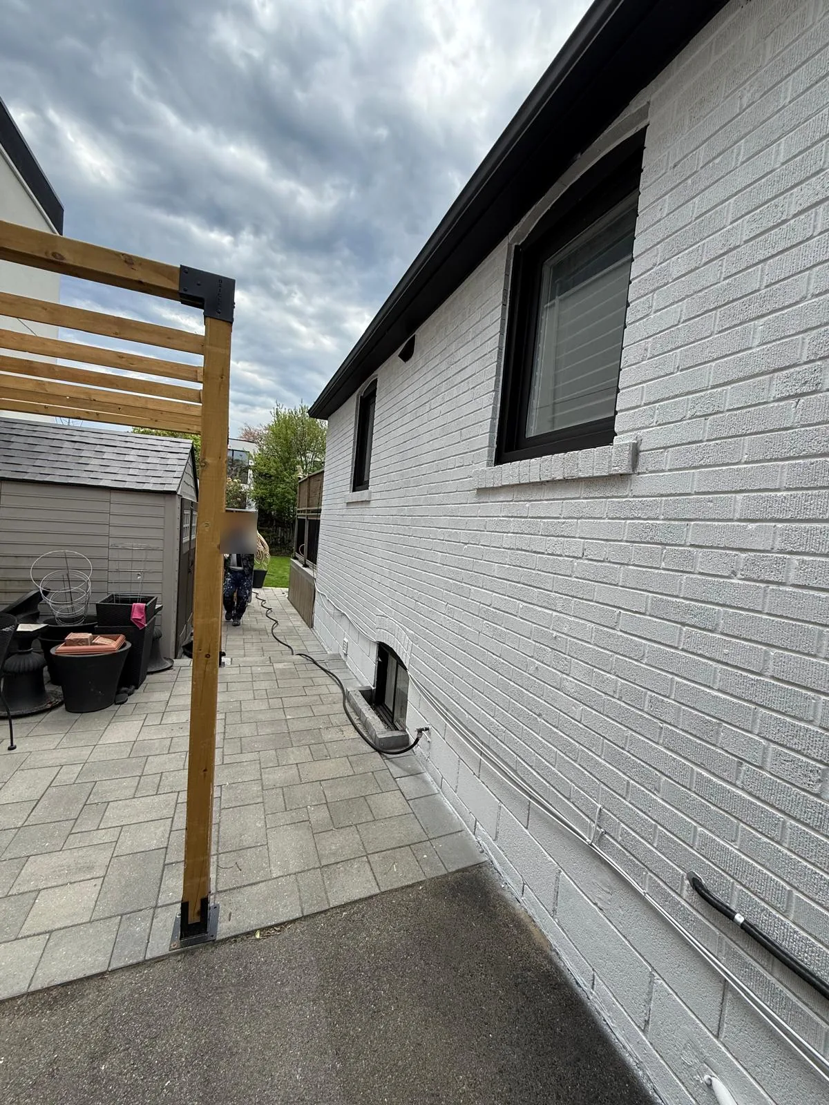 After: the side of the house in white painted brick with black window frames and gutters
