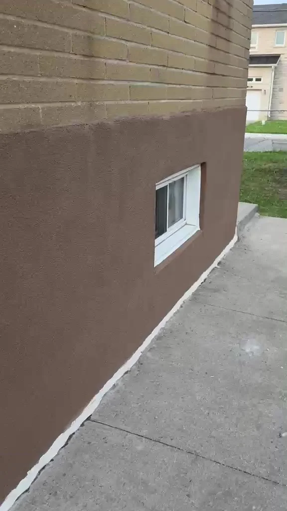 Finished foundation wall with a dead-straight brick line and a clean caulked edge along the walkway