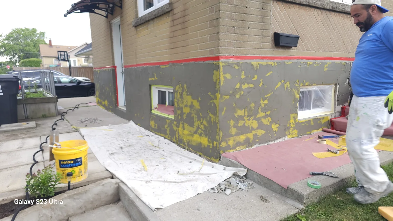 Foundation wrapped in grey base coat around the corner with the top line kept straight against the brick