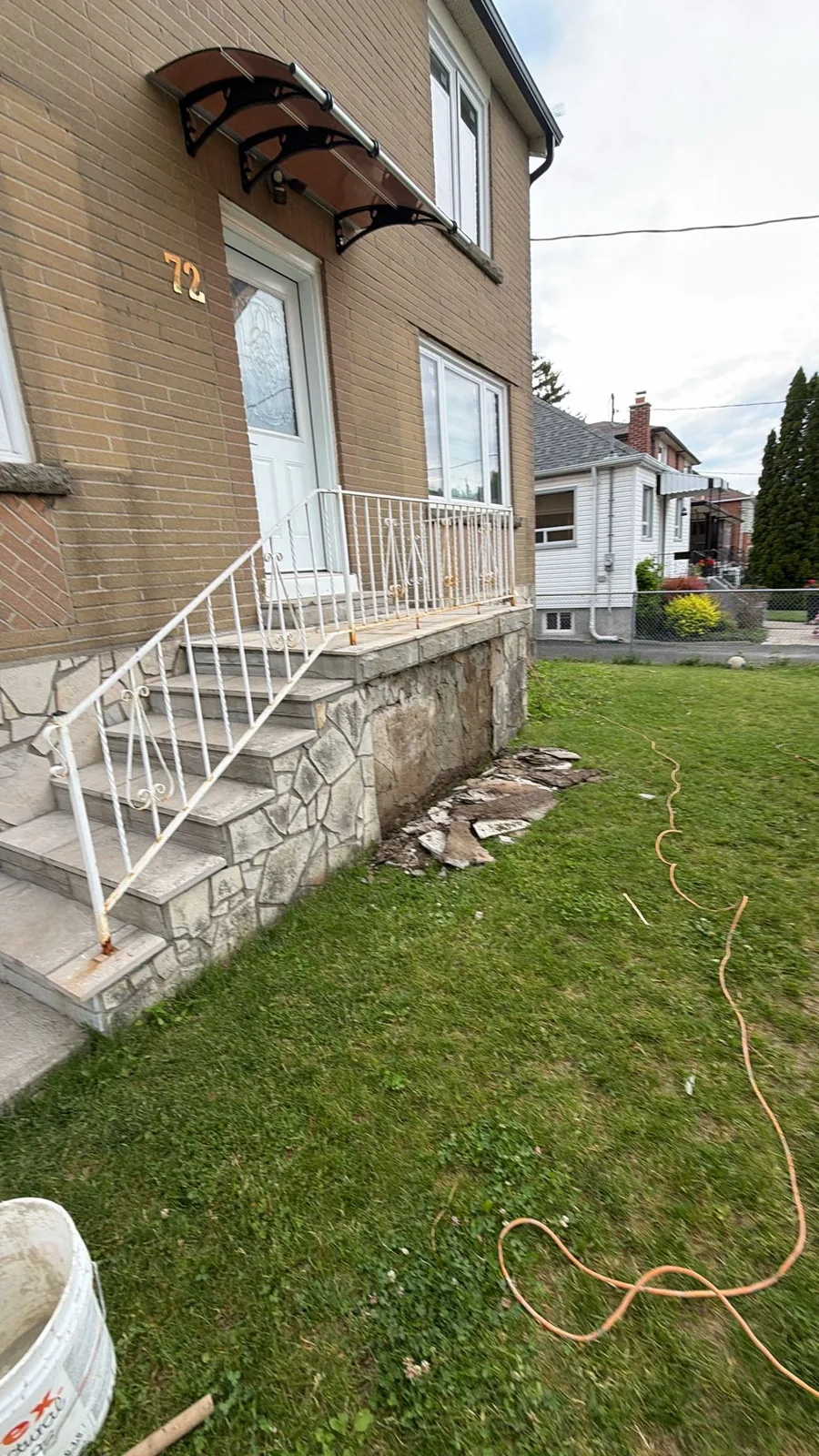 Front entrance and steps with old stone veneer foundation before work