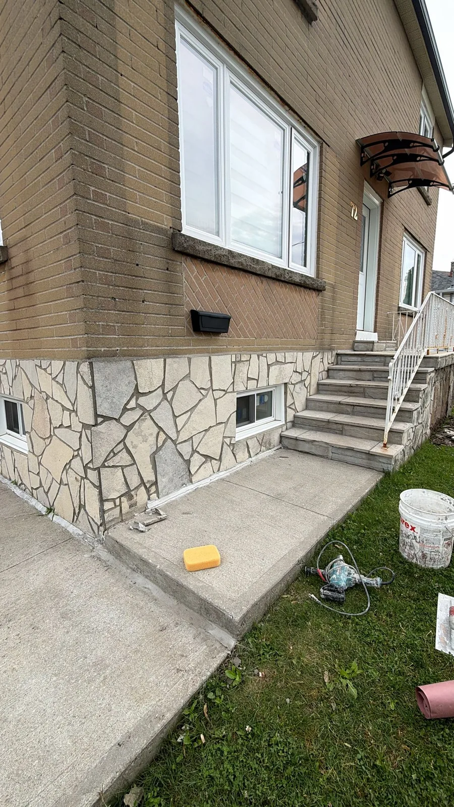 Home front foundation clad in dated stone veneer before refinishing
