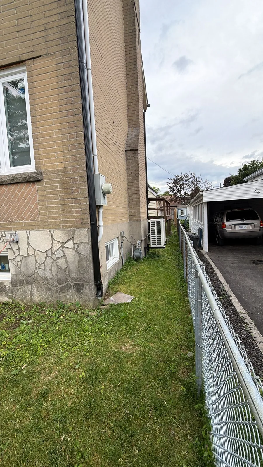 Side wall foundation with old stone veneer and an AC unit before refinishing