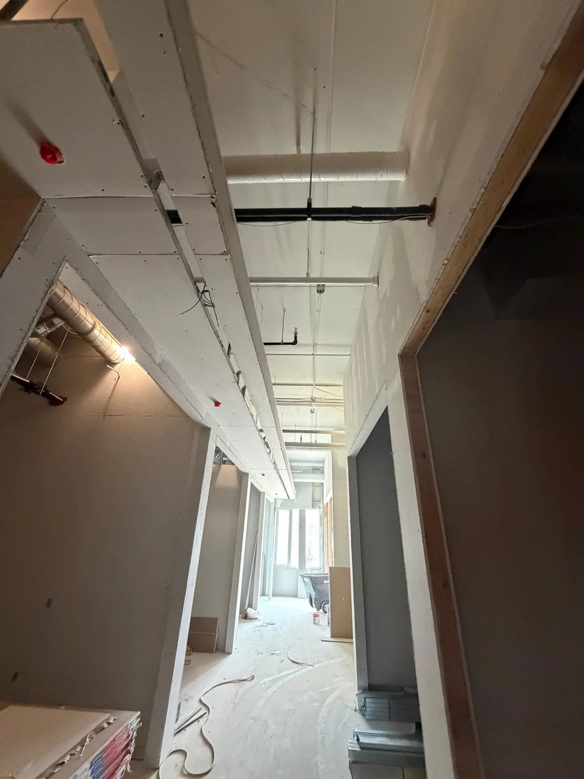 Corridor with finished drywall bulkheads, painted ceiling and a sprinkler head left clear of coating