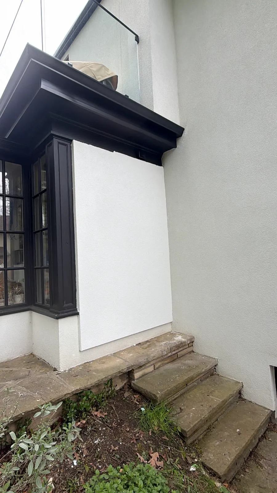 House wall finished in seamless smooth white, blended into the original facade