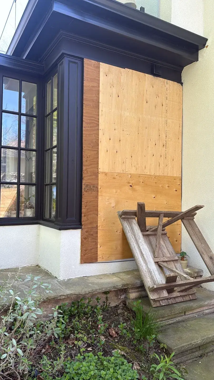 House wall opening sheathed in plywood beside the bay window, before stucco infill