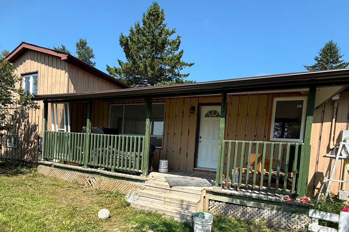 The Innisfil bungalow before work started, showing the original weathered vertical board exterior and green porch
