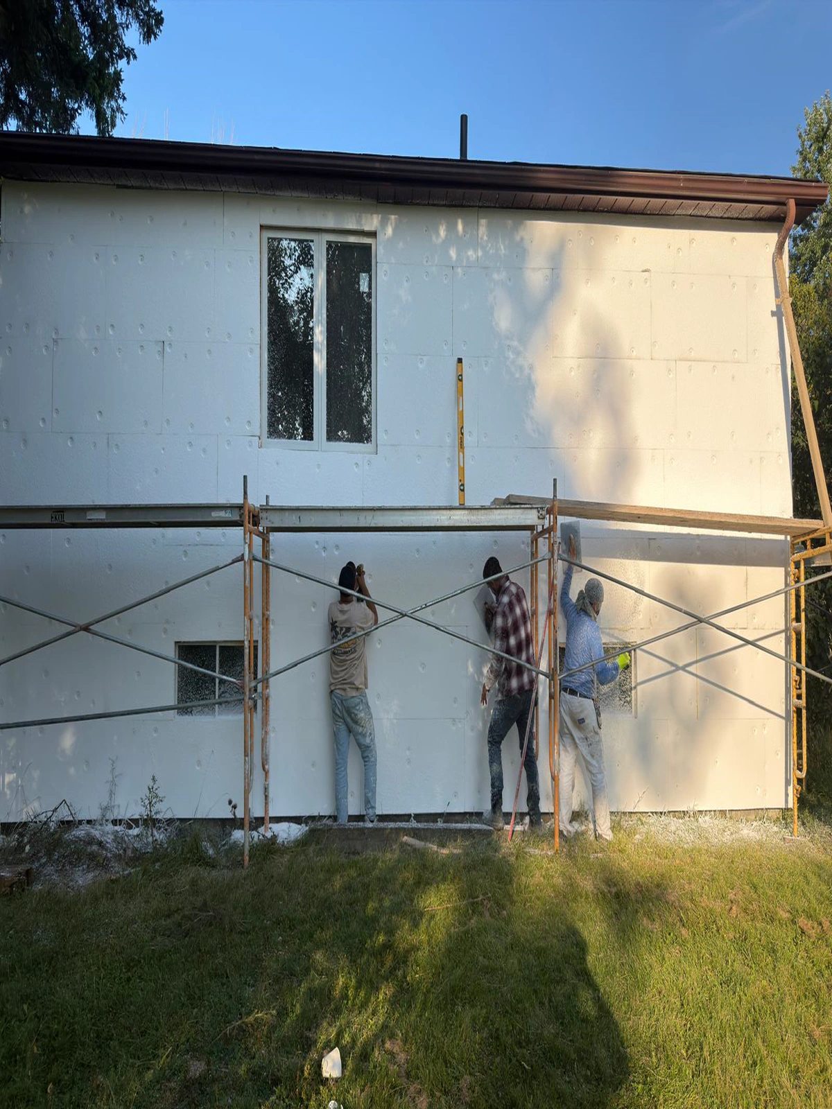 FAIME crew working the base coat across the insulation board face from scaffold