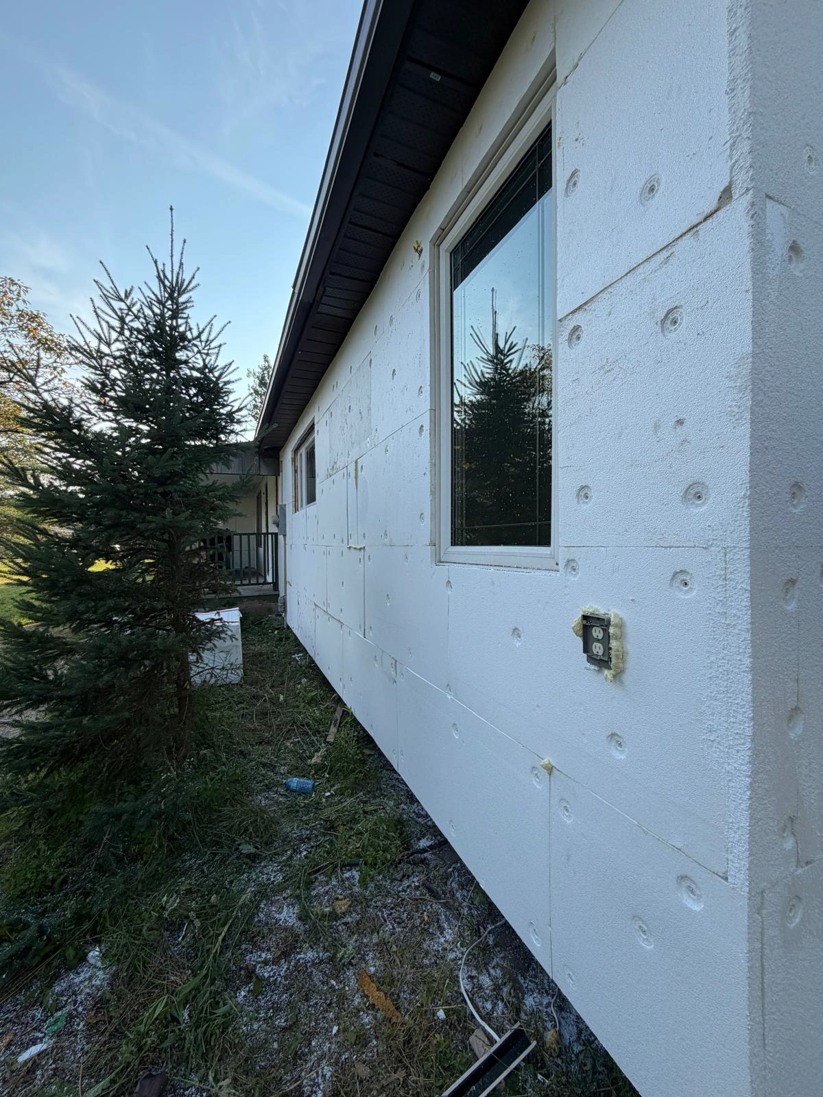 EPS insulation board fixed across the wall face of the bungalow, straightening the elevation