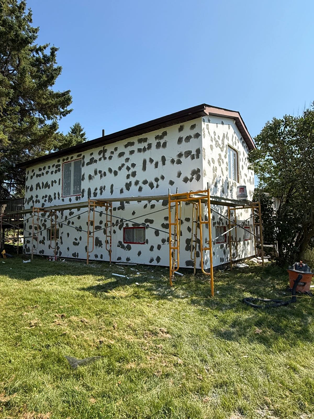 Insulation boards with every fastener head spotted with base coat, drying before the full coat goes on