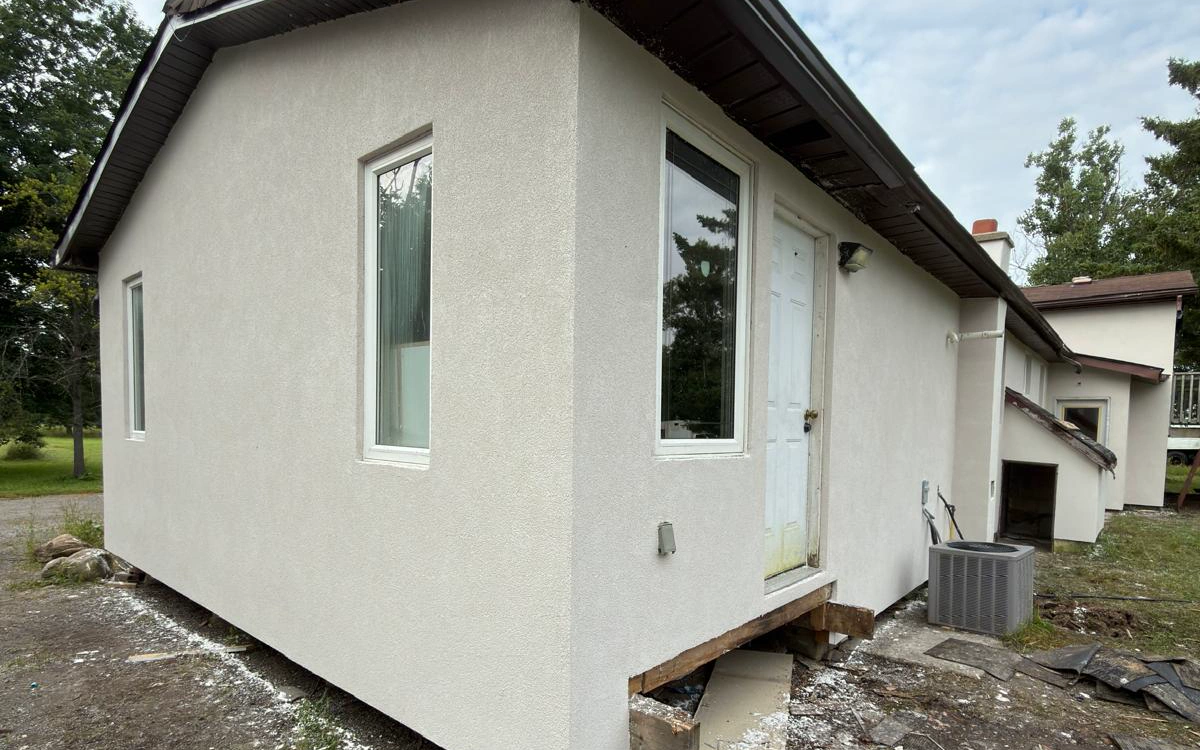 The finished corner of an Innisfil bungalow after a full exterior EIFS transformation by FAIME Construction, showing a flat textured finish coat and clean window returns