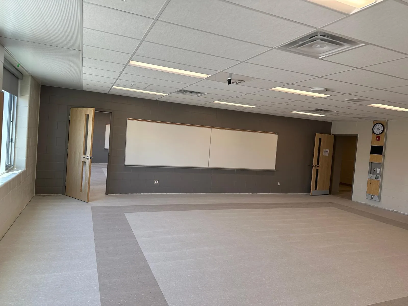 A classroom with a grey accent wall, white boards and painted door frames
