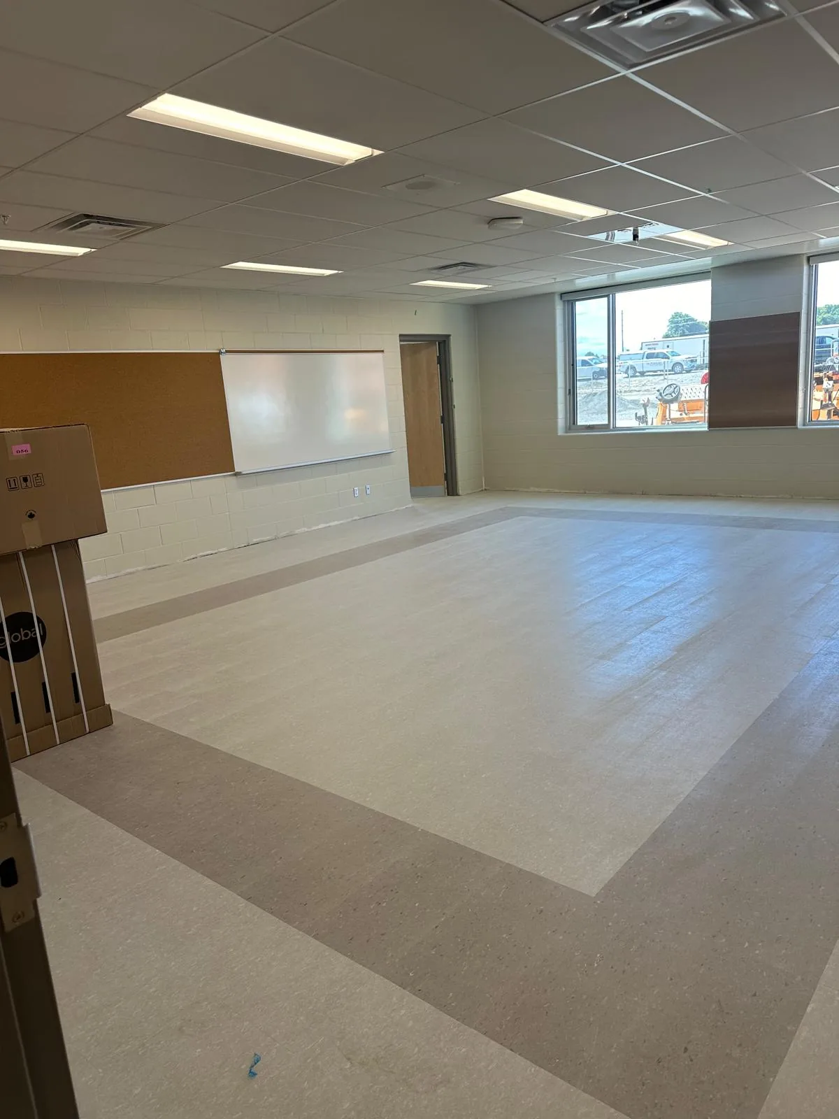 A finished classroom with a tackboard and whiteboard mounted on freshly painted walls