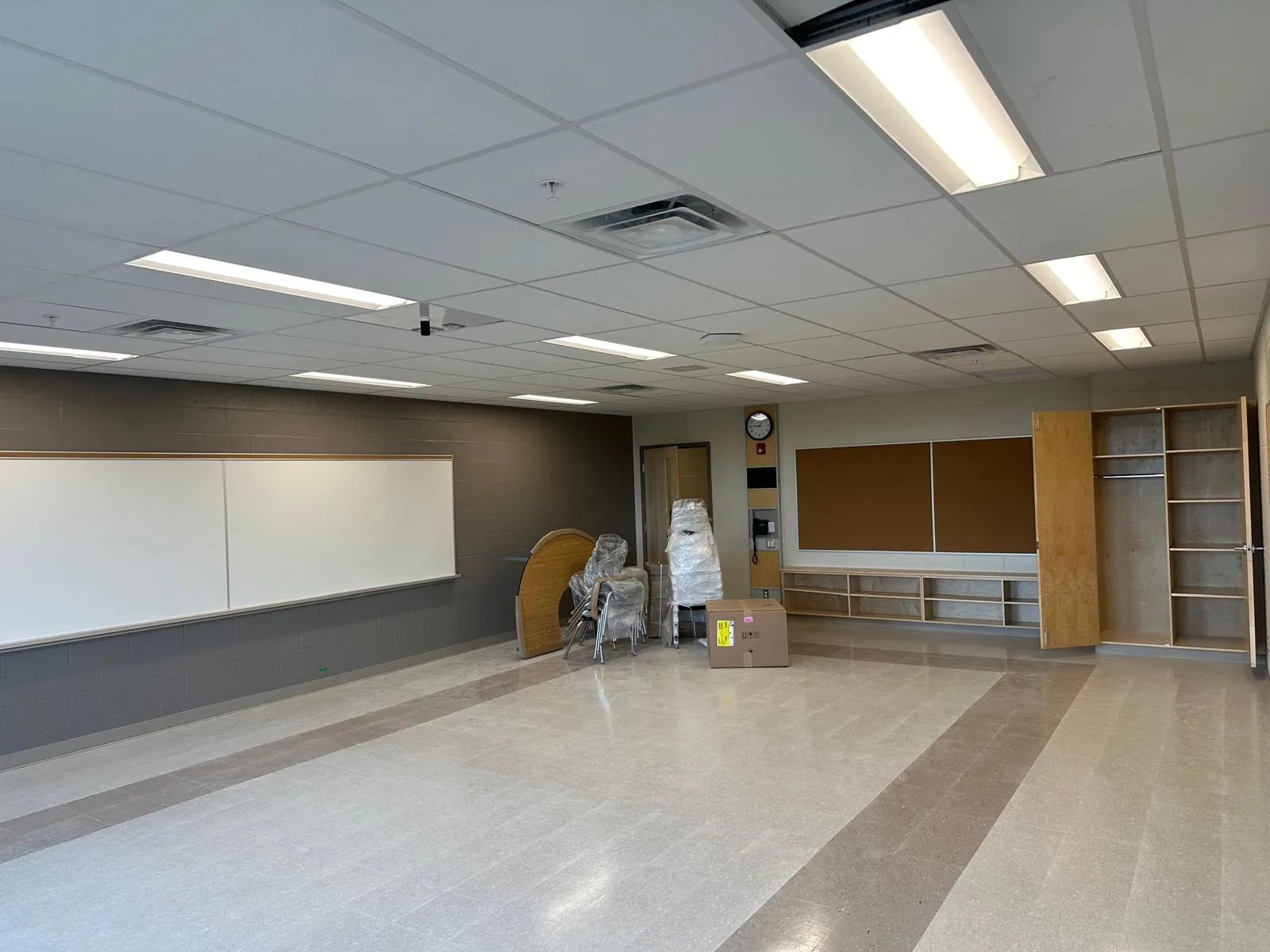 A classroom with a grey accent wall and storage cabinets, before furniture was set up