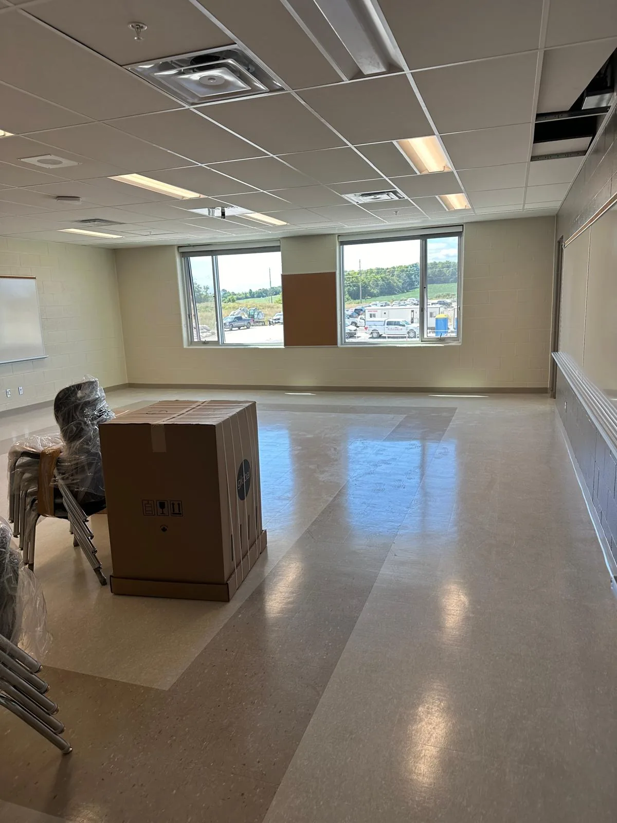 A bright classroom with light walls and large windows, ready for furniture