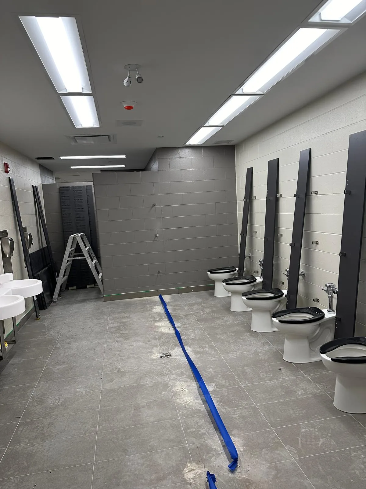 A washroom with painted block walls, before the stall partitions were installed