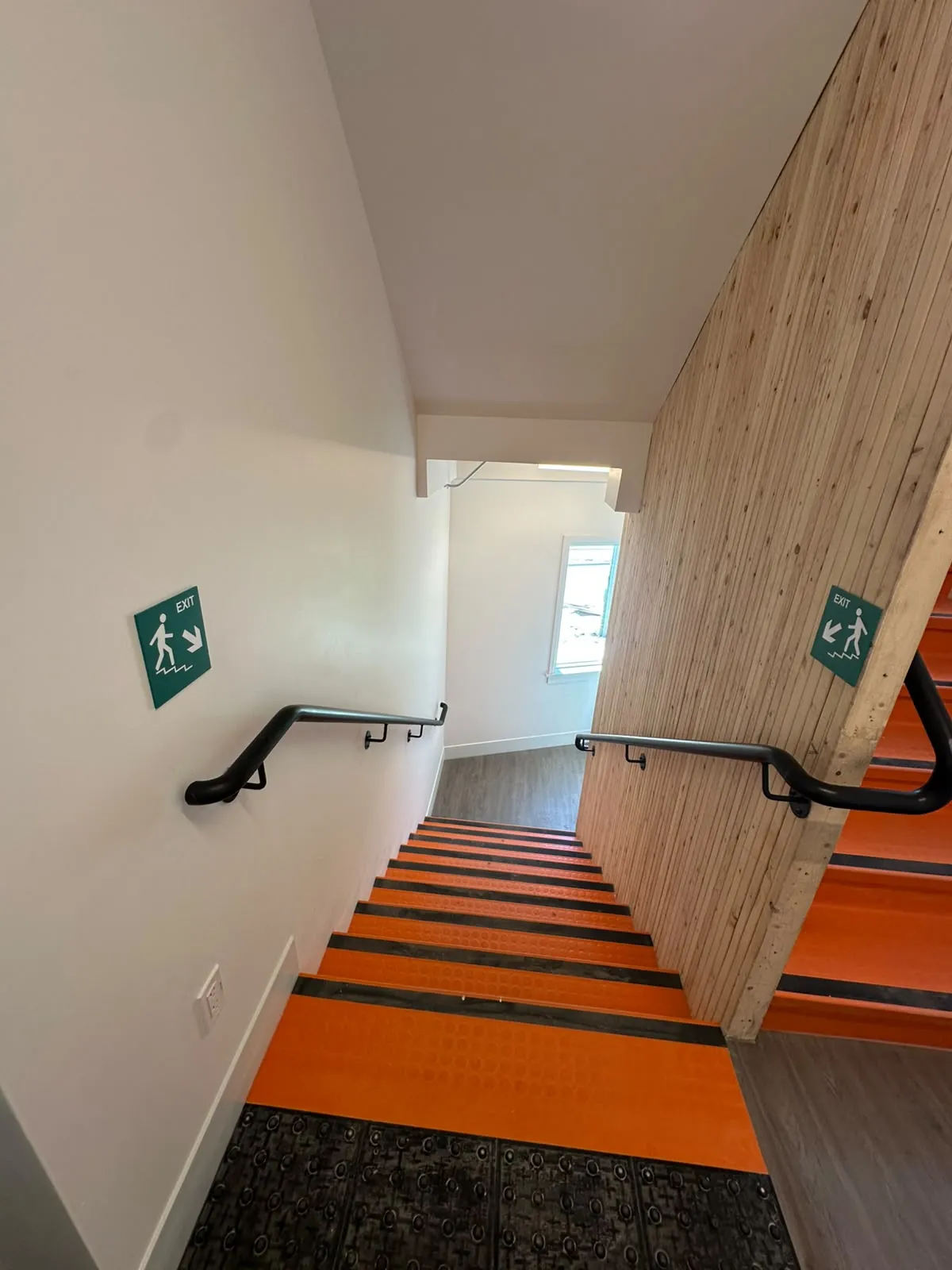 A stairwell with painted walls beside a natural timber wall and handrails