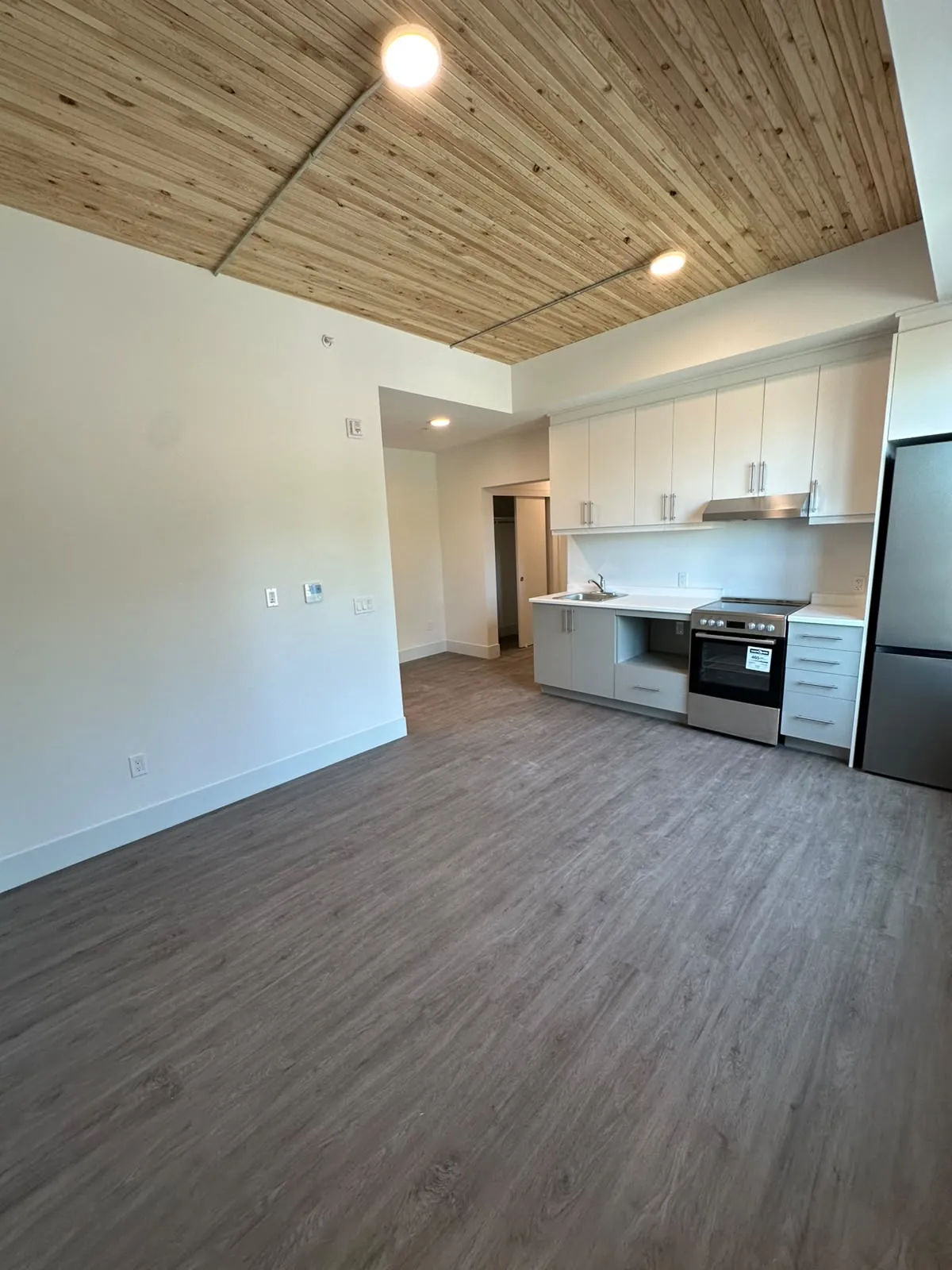 A suite kitchen and living area with painted walls under a timber ceiling