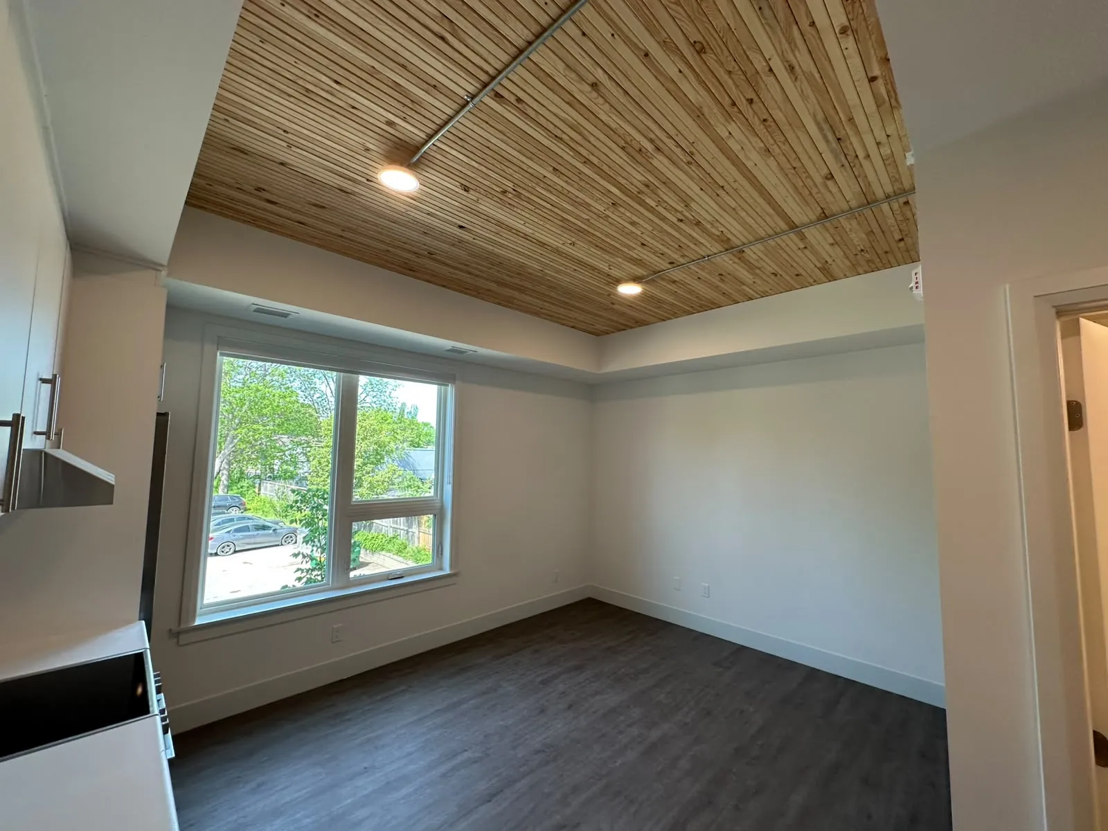 A finished suite room with painted walls, a large window and an exposed timber ceiling
