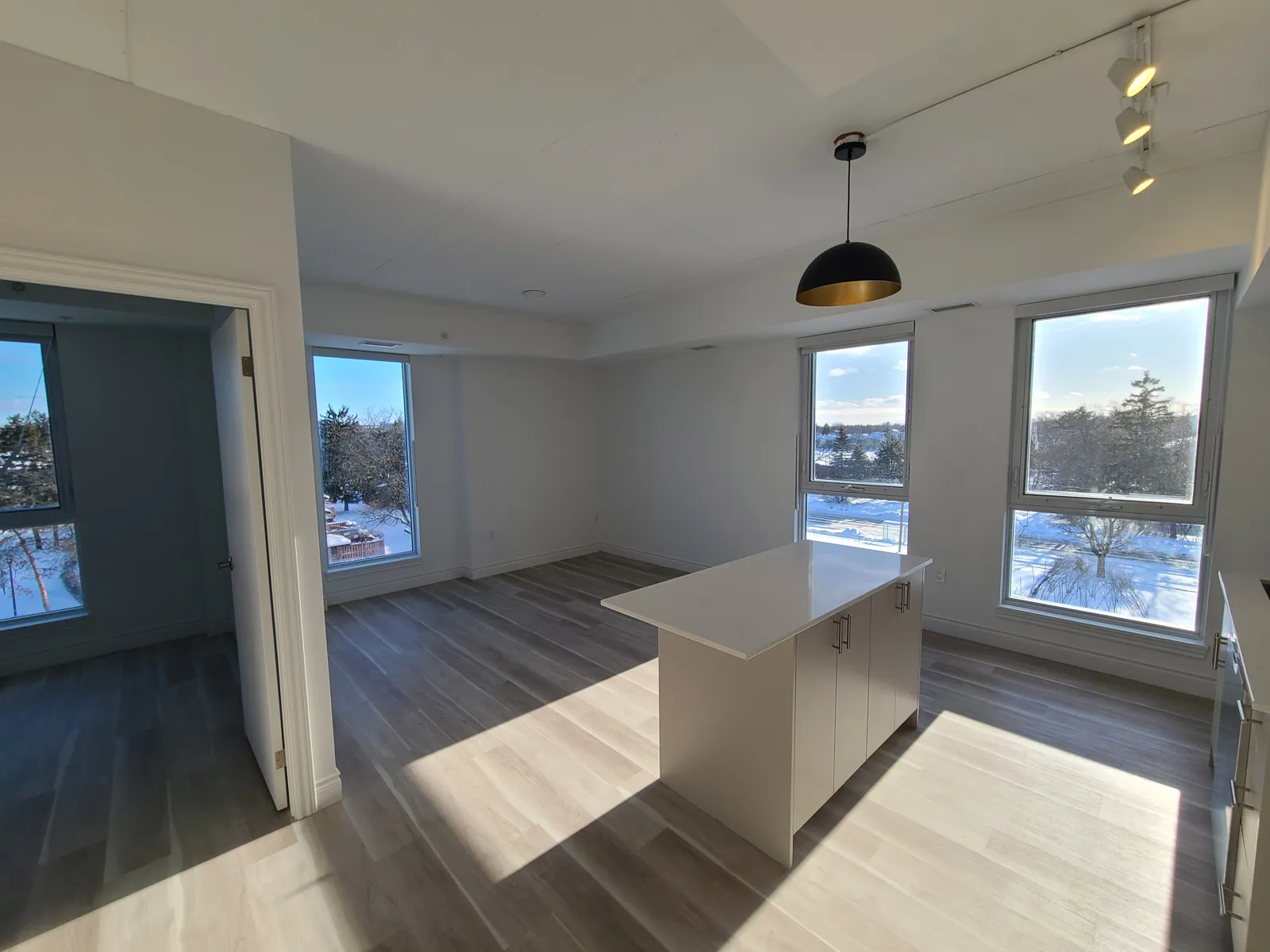 A corner suite living area with painted walls, an open bedroom door and windows on two sides