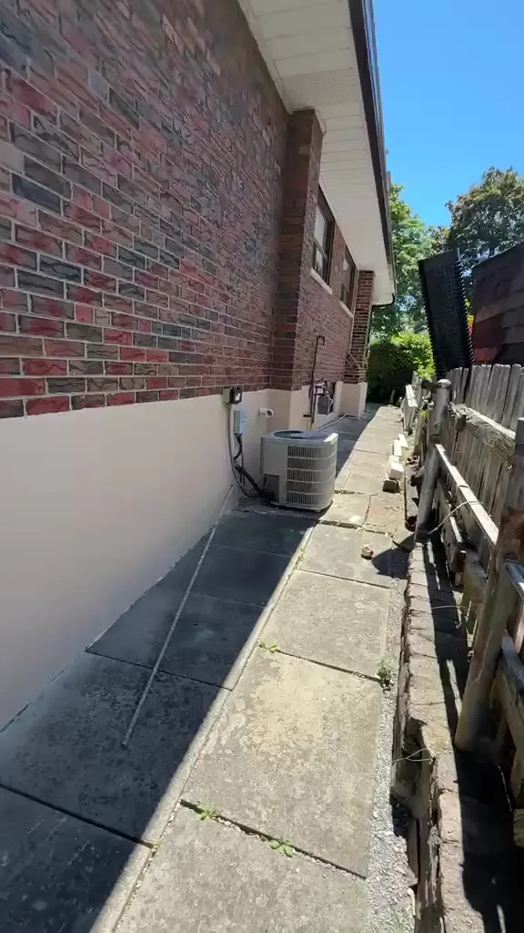 Finished side walkway wall with a clean caulked base by the AC unit