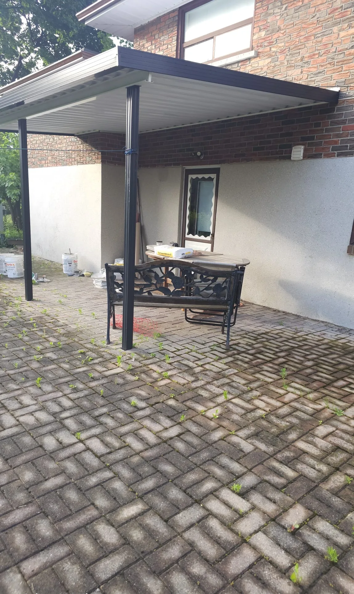 Rear door wall with the old coating before grinding, materials staged on the patio