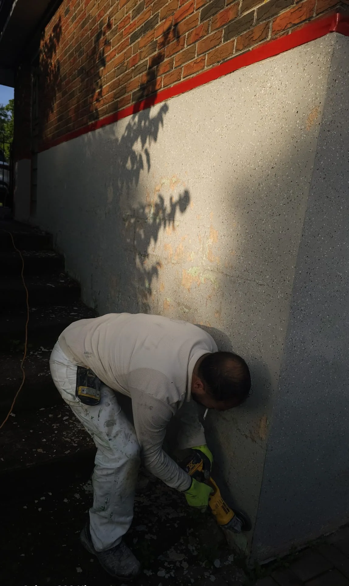 FAIME tradesperson grinding the old coating off the corner of the wall with a grinding machine