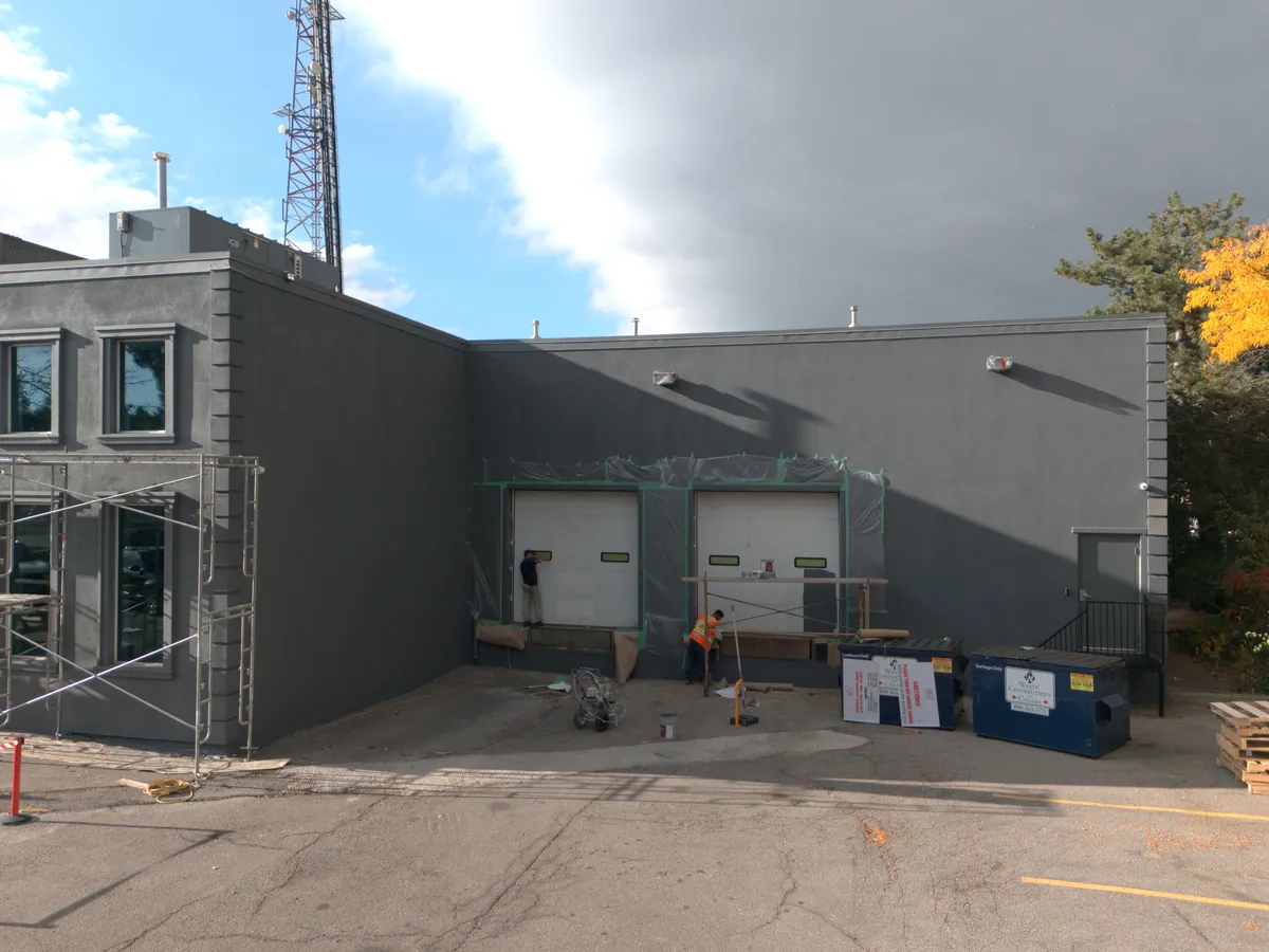 Drone view of the loading-dock elevation finished in dark grey, dock doors masked and the crew finishing up