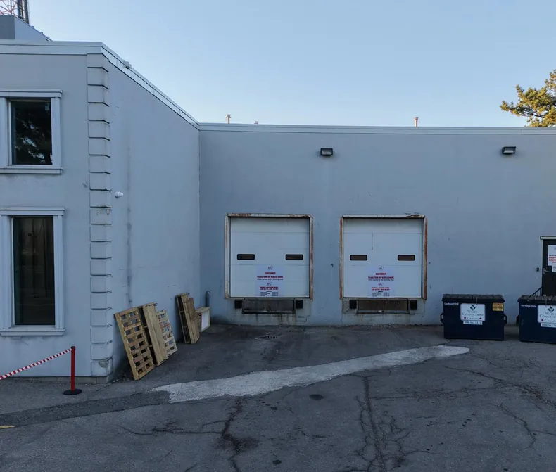 The same loading-dock elevation before work, in a faded cream finish with rust at the dock-door frames