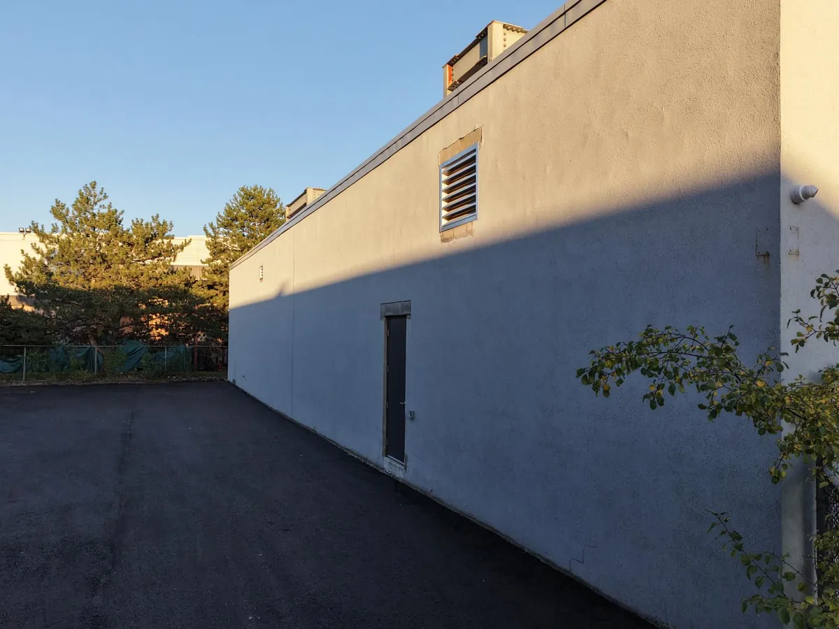 The long rear wall before work, a single flat run of weathered finish