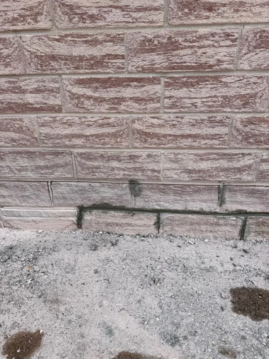 Brick repair at the base of a wall, new mortar pointed into the damaged joints
