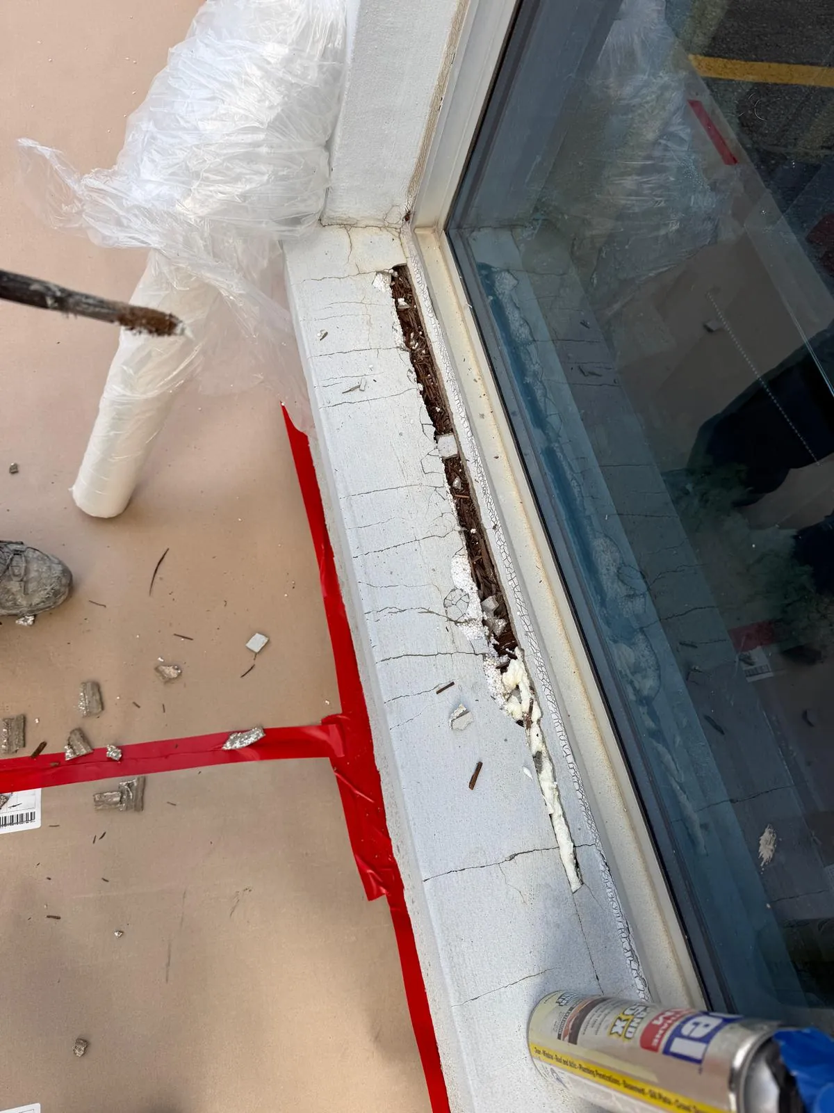 The old window caulking being cut out along a sill, with the floor protected