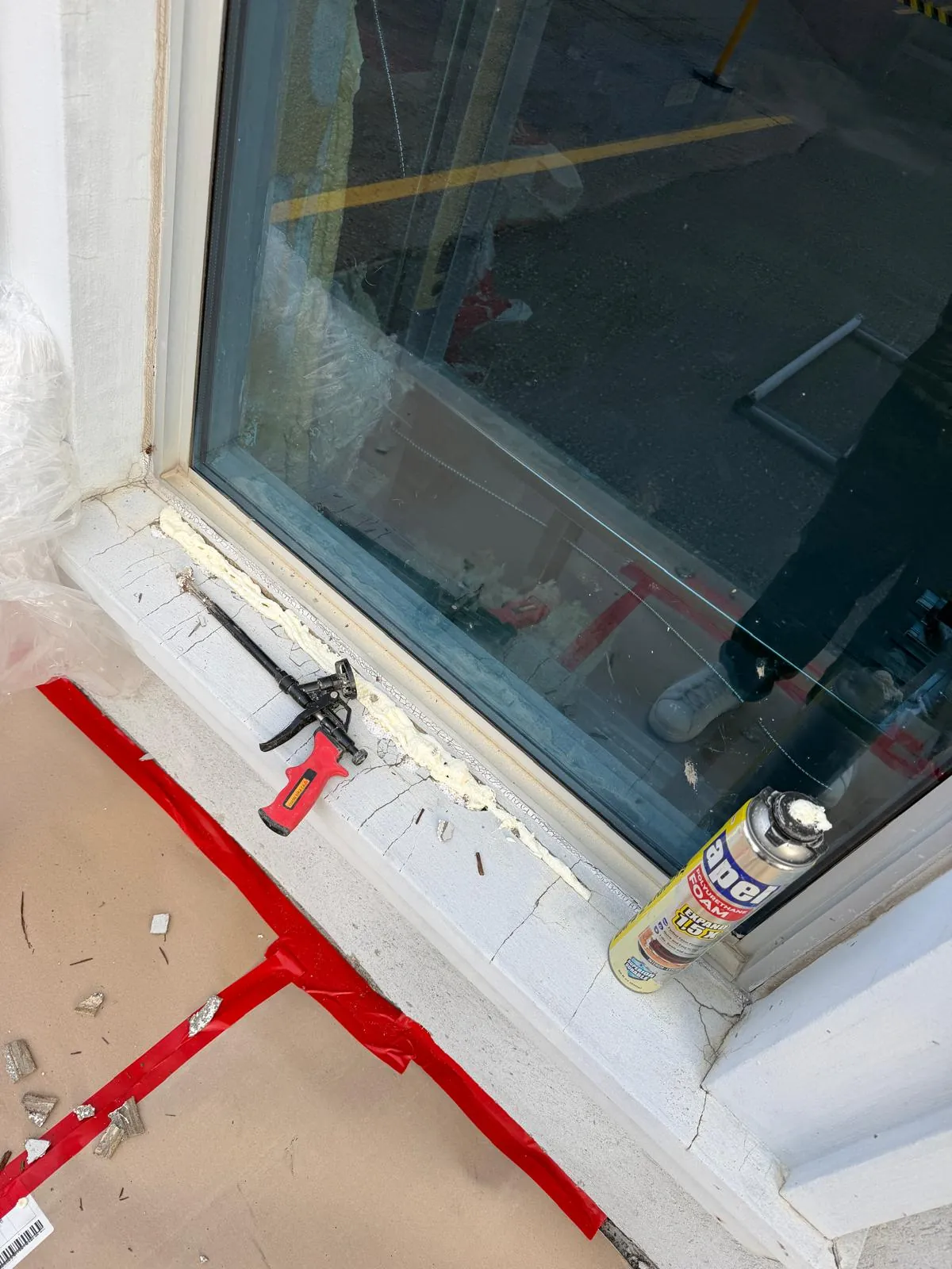 A window sill cleaned back and ready for new caulking, cartridge and gun on the protected floor