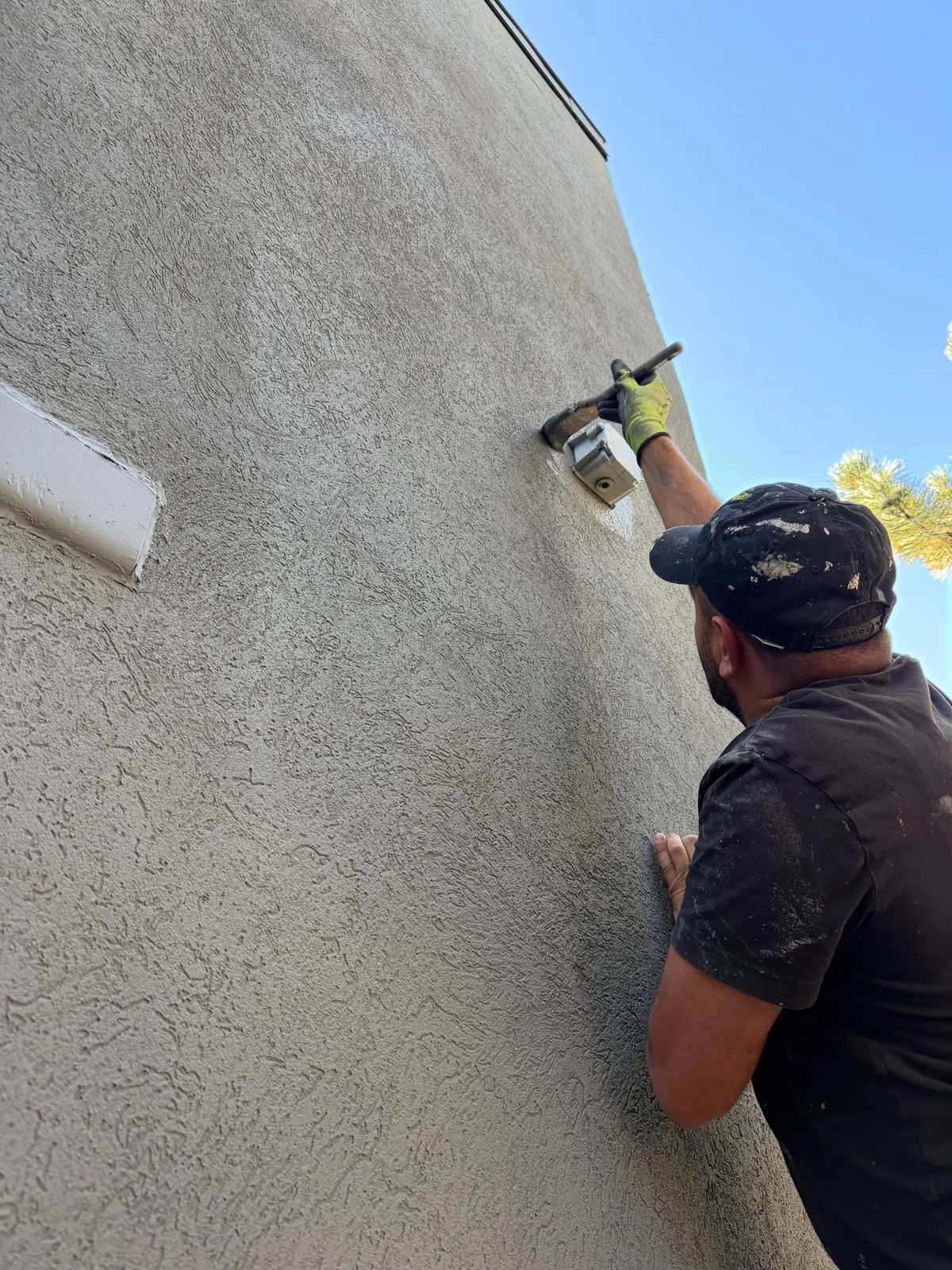A FAIME painter brushing the new grey tight around a wall-mounted light