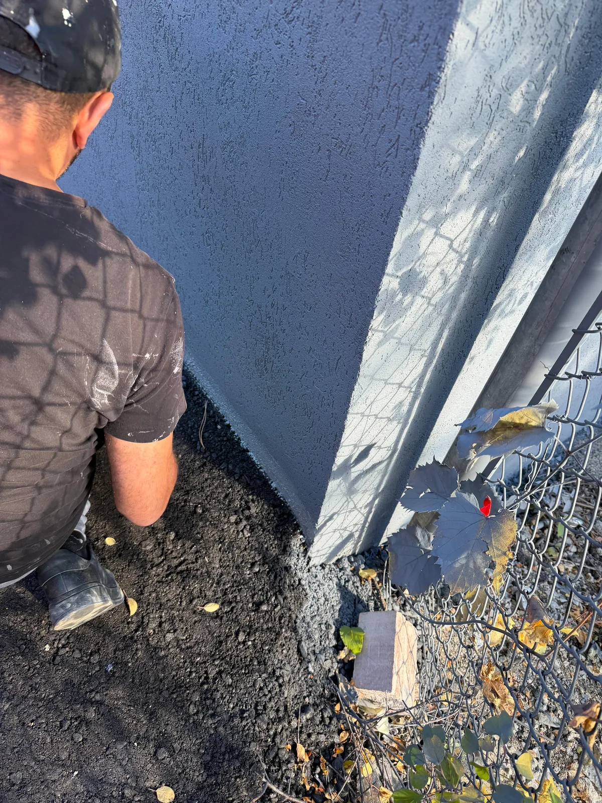 A FAIME painter crouched at the base of the wall, cutting in the new grey along the ground line