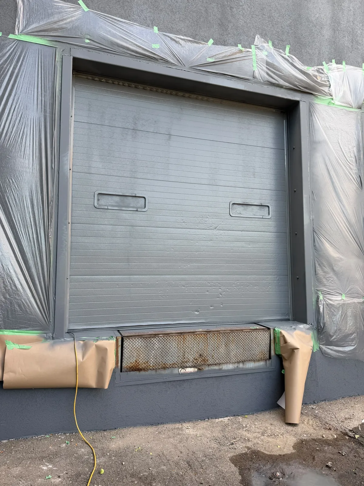 A loading-dock door with poly around the frame and paper protecting the bumper below