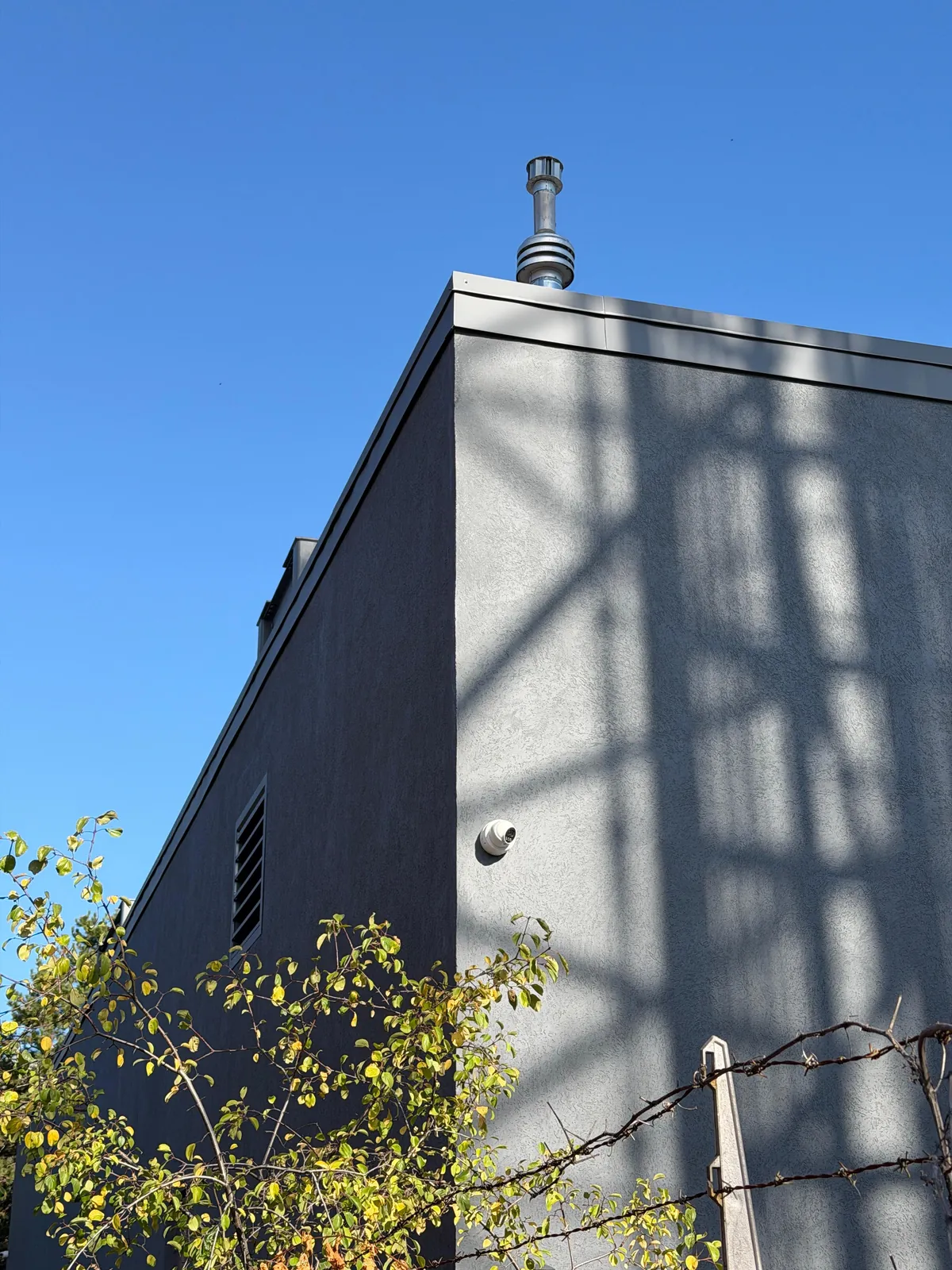 The finished upper wall and roof edge in dark grey against a clear sky