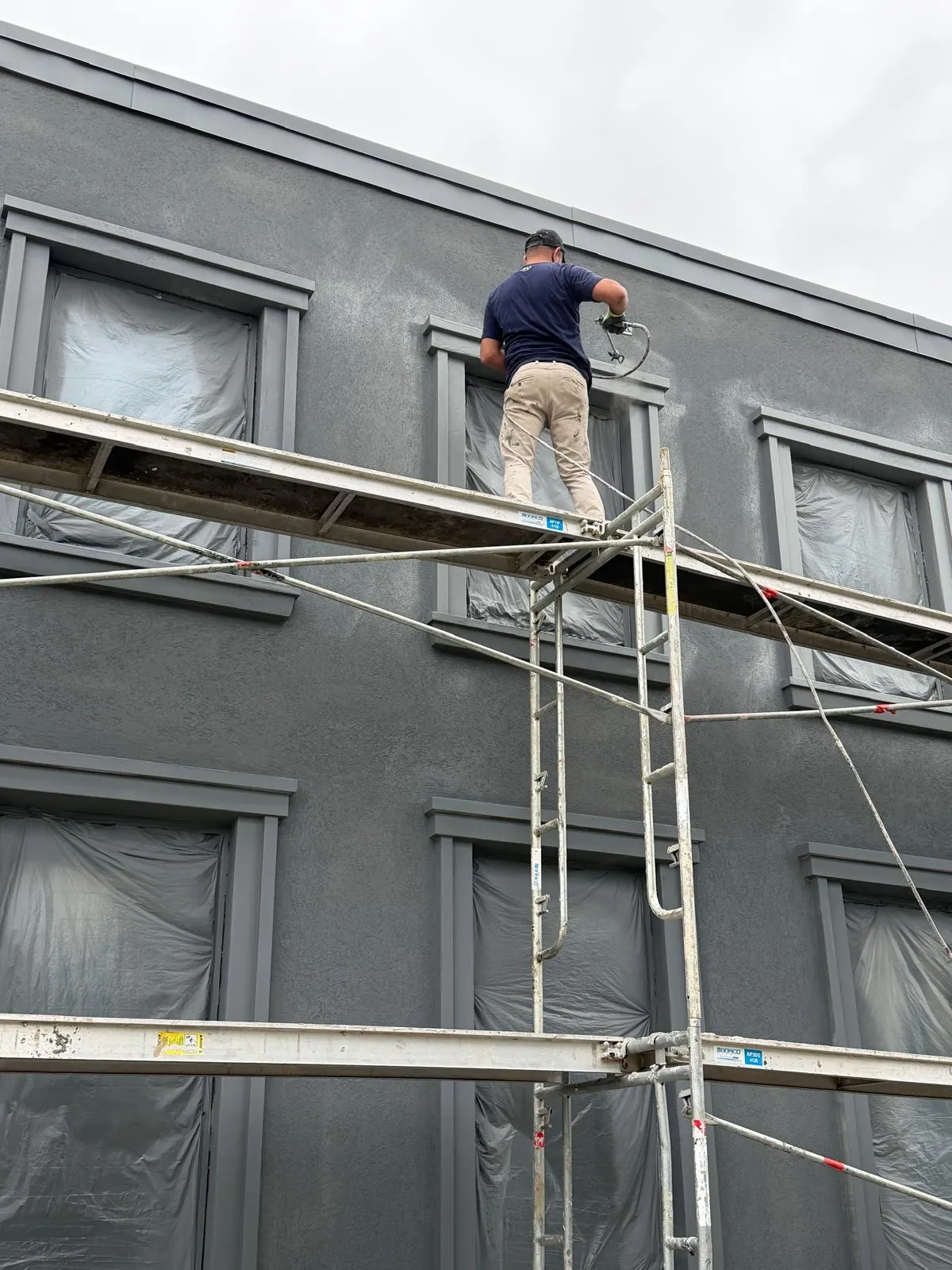 A FAIME crew member working from scaffold beside masked windows on the upper wall