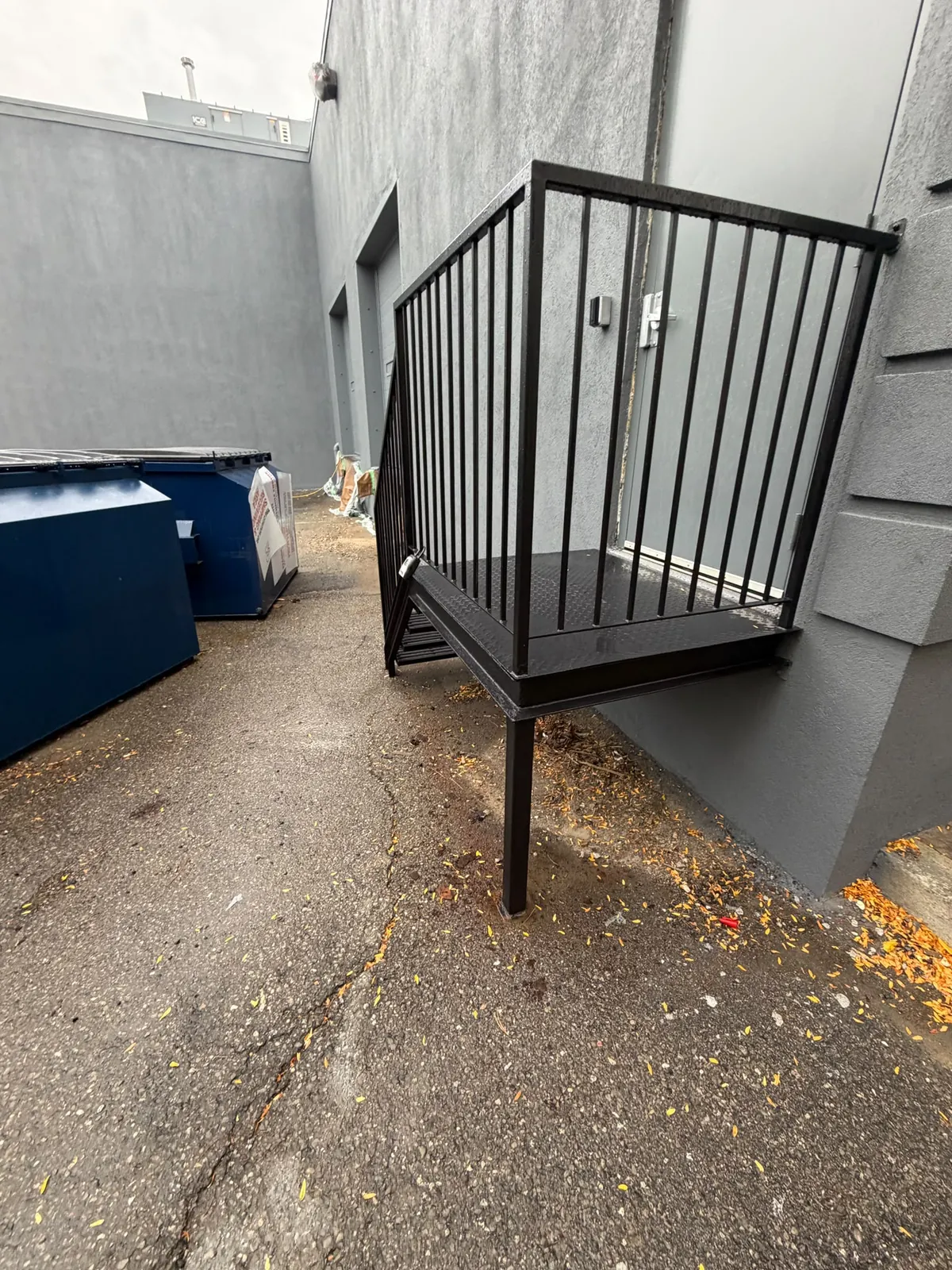 A steel exit stair and landing with railings, freshly painted black