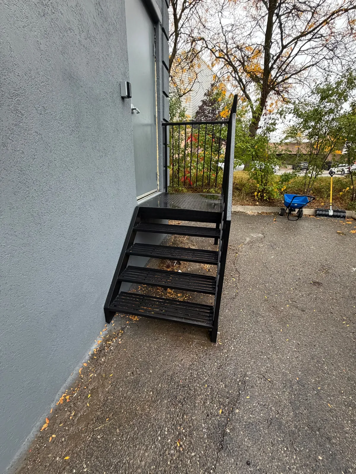 A side-entry steel stair painted black against the finished grey wall