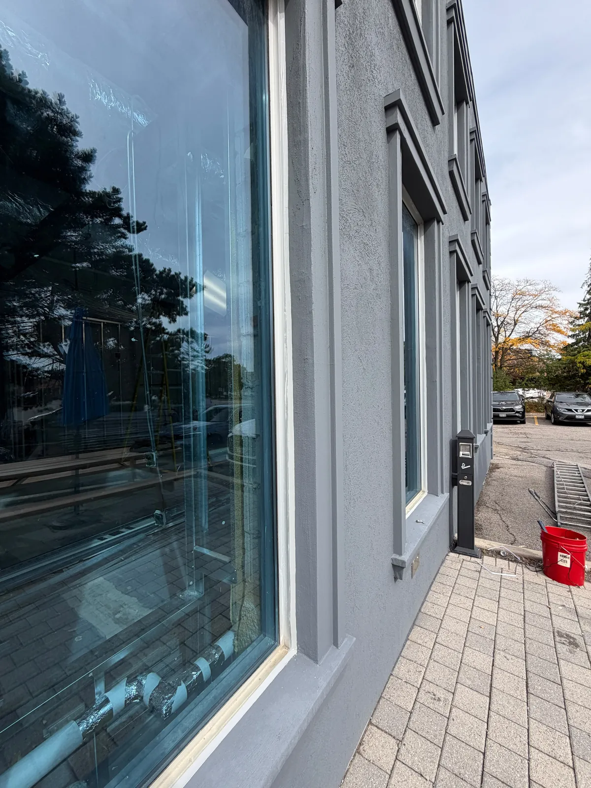 A large storefront window, re-caulked, with the finished grey wall running down the walkway