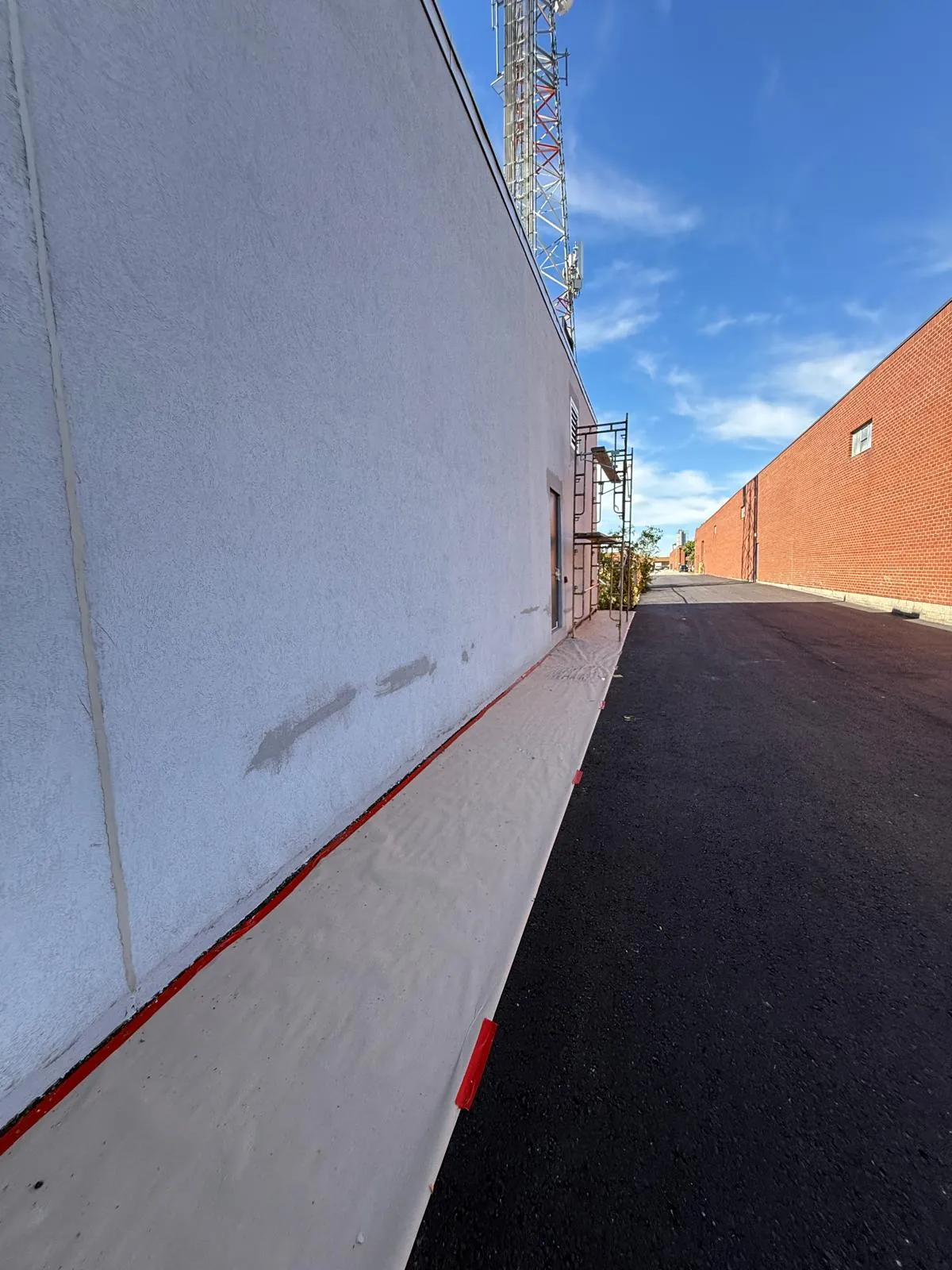 Freshly patched stucco damage along the long wall, over drop sheets
